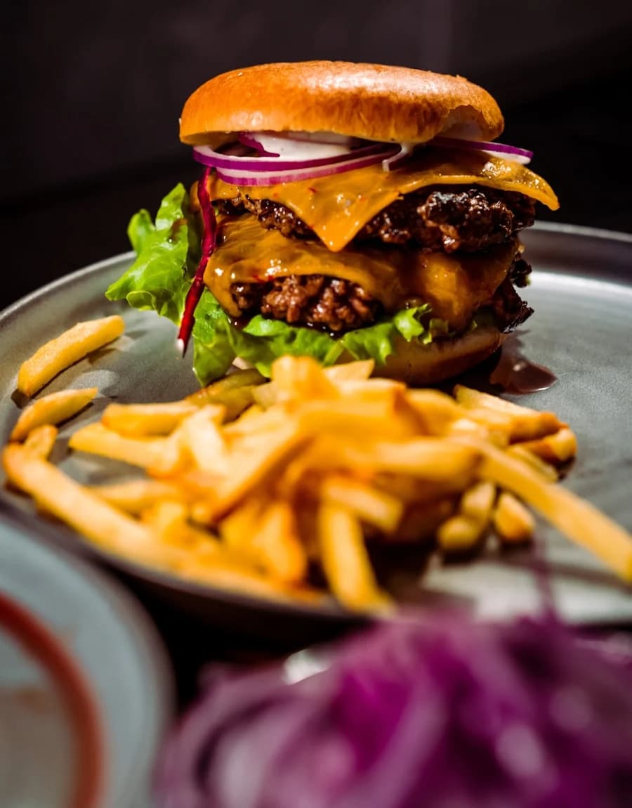 Double cheeseburger and fries on a dark plate
